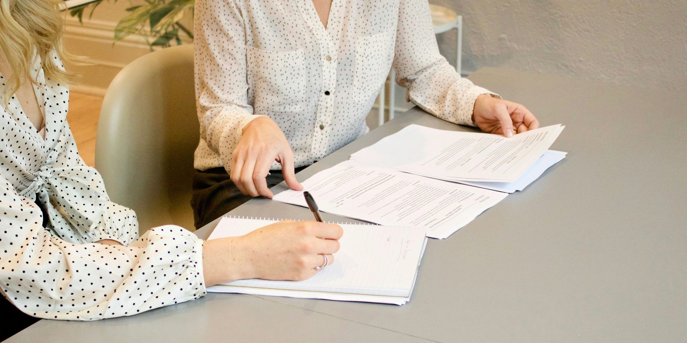 Dos personas revisan y firman documentos sobre una mesa clara