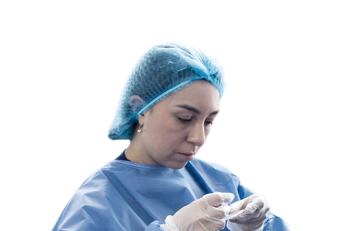 Profesional de CAIMED con gorro y bata prepara una muestra en el laboratorio
